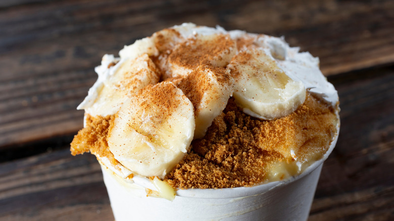 A cup of banana pudding topped with sliced bananas and spices
