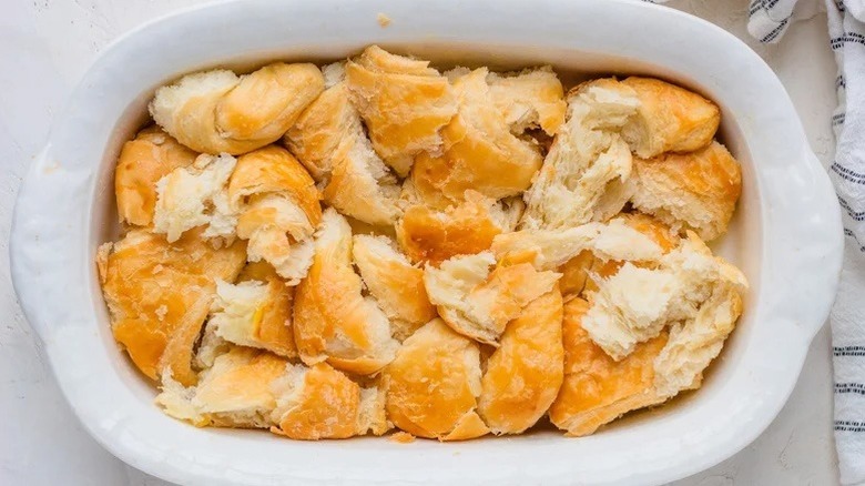 Pieces of ripped up croissant in the bottom of a baking dish