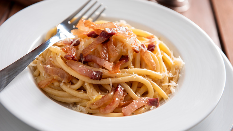 Bucatini pasta in white bowl with fork