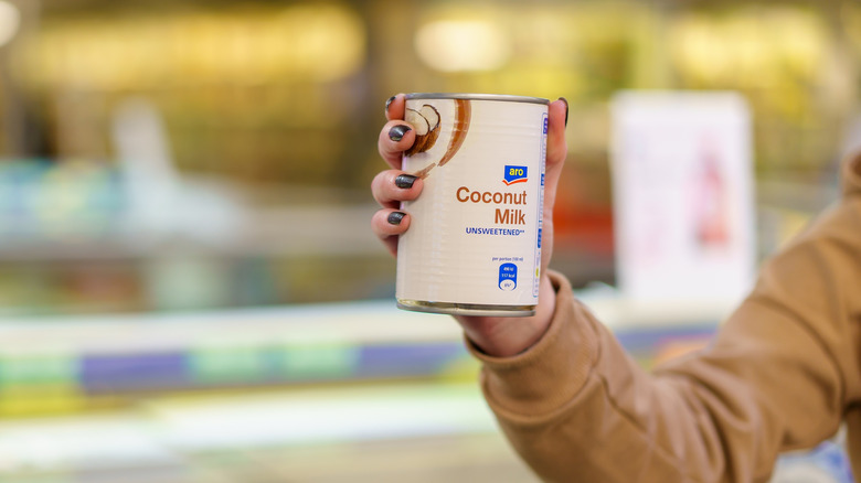 woman holding a can of coconut milk in hand