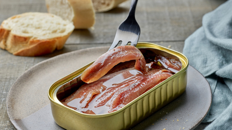 Fork with can of anchovies and bread