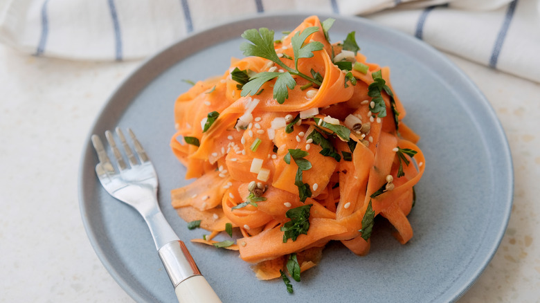 Carrot ribbon salad on a plate with sesame seeds and herbs