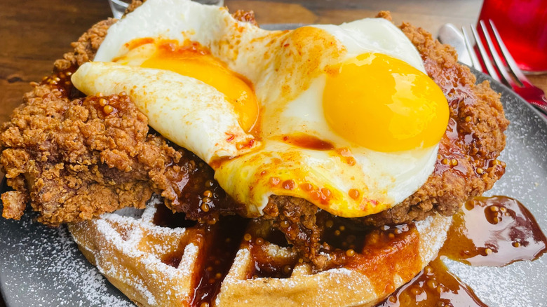 a plate of chicken and waffles topped with fried eggs