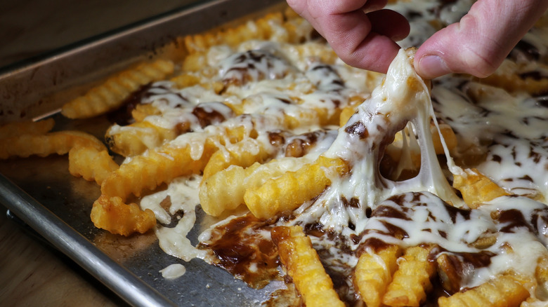 fingers picking up disco fry and stretching melted cheese