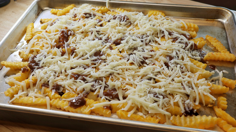 sheet pan of crinkle cut fries topped with gravy and grated cheese