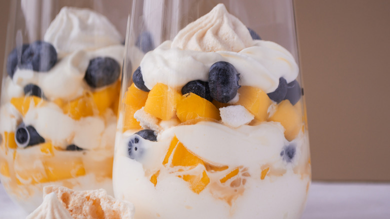 Close up Eton mess with whipped cream, meringue, fresh blackberries and mango