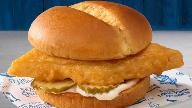Long John Silver's fish sandwich on wrapper with sauce and pickles