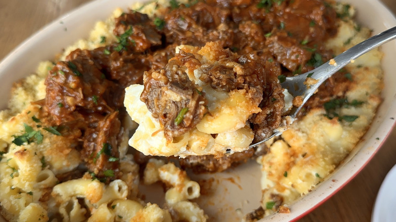 Mac and cheese with meat on a spoon.