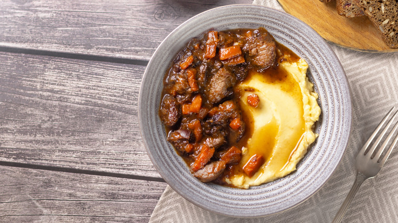 Beef stew atop mashed potatoes