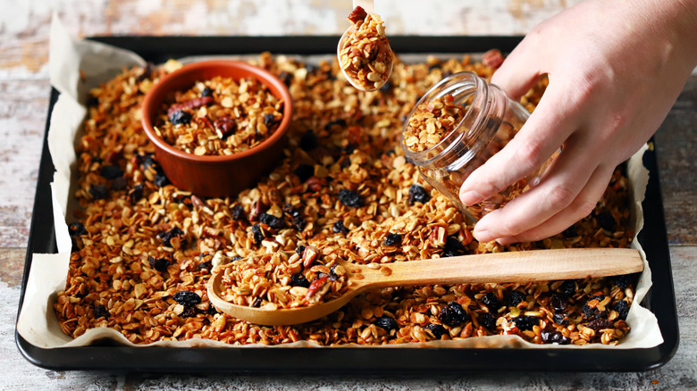 grape nuts cereal on baking sheet with wooden spoon and glass jar