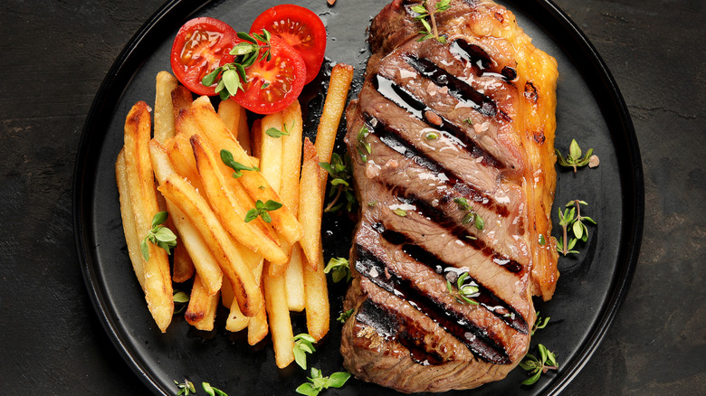 A plate of steak frites with tomatoes