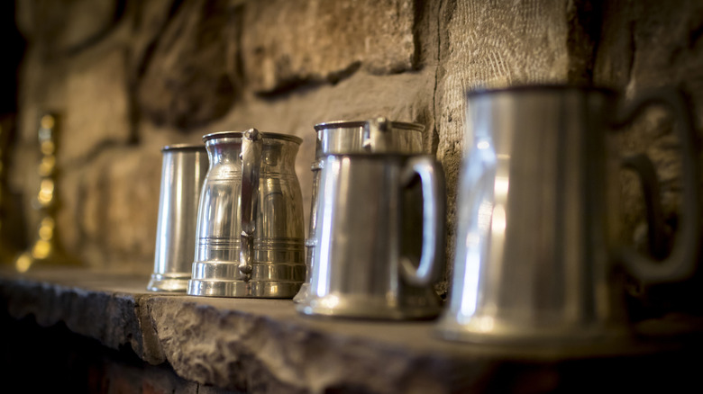 Traditional pewter mugs on shelf