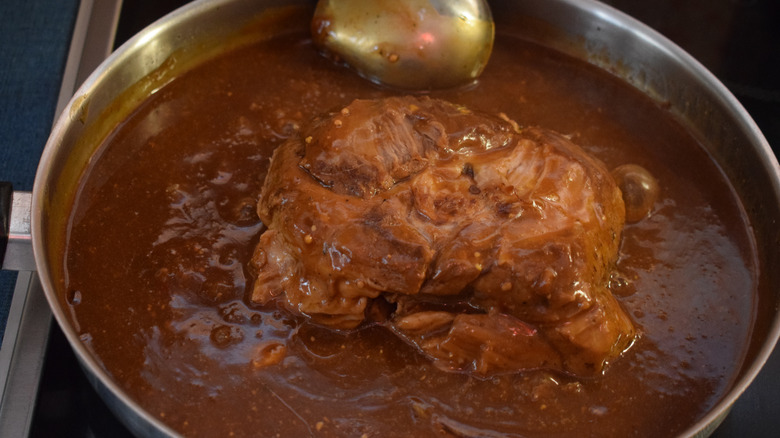 A top view of a pot roast in liquid