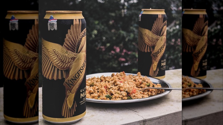 A plate of rice in between two cans of beer