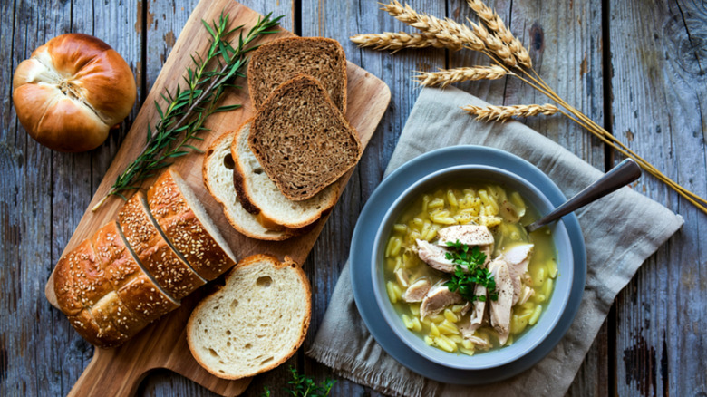 Rye bread loaf next to bowl of chicken noodle soup