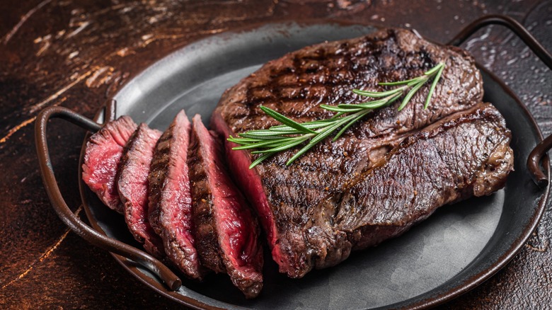 A beautifully grilled and sliced sirloin steak is on a platter.