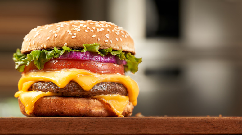 Cheeseburger with sliced tomato, red onion, and lettuce