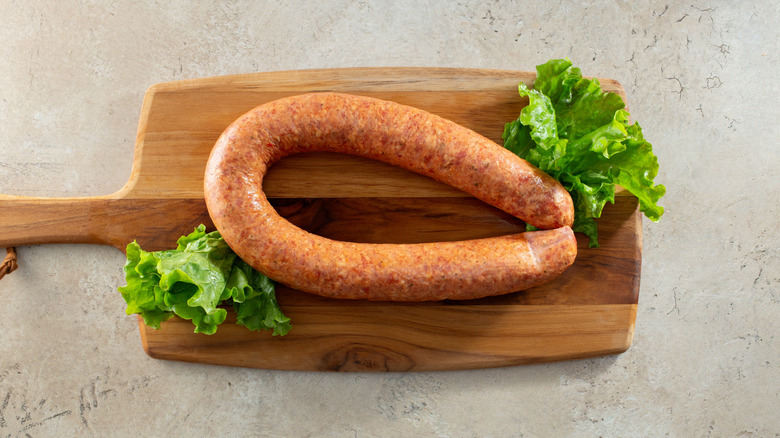 Andouille sausage on wooden board with lettuce leaves