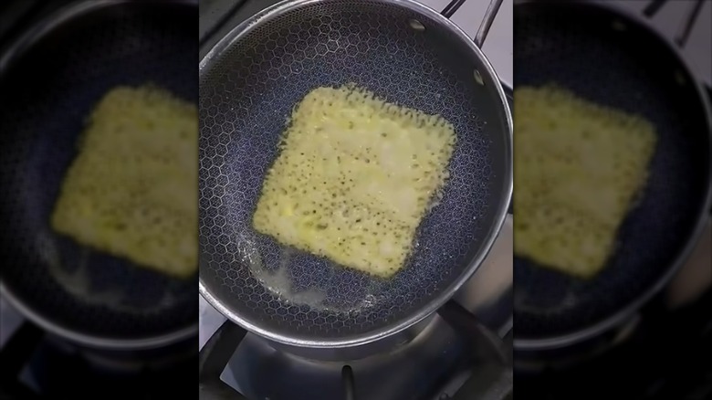 Slice of cheese caramelizing in skillet