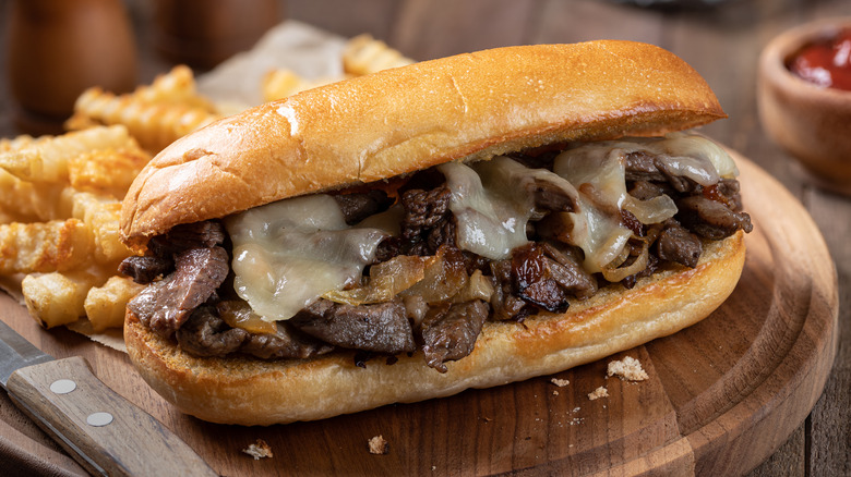 Cheesesteak on wooden cutting board with fries
