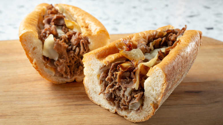 Cheesesteak sandwich cut in half on wooden surface