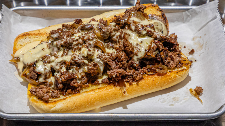 Cheesy cheesesteak on metal tray with parchment paper
