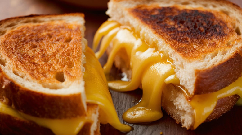 Grilled cheese sandwich cut in half with orange cheese oozing out