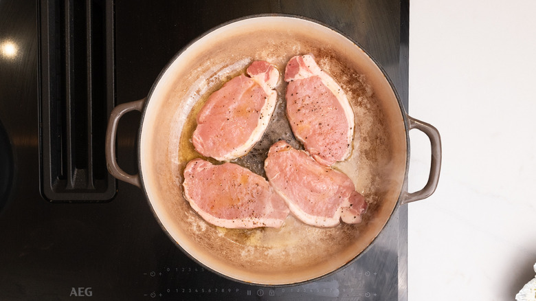 pork chops cooking in pan