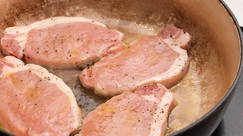 pork chops cooking in pan