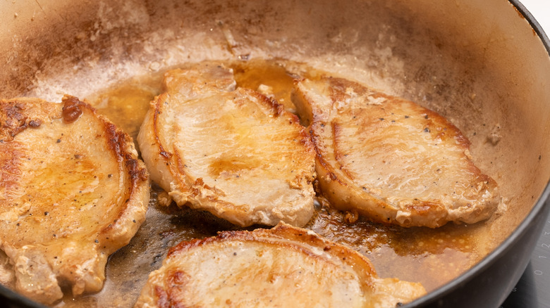 pork chops cooking in pan