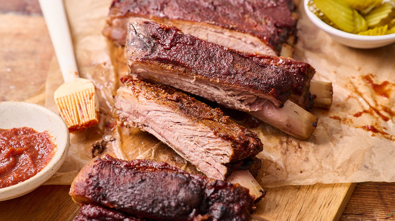 Baked and cut St. Louis-style ribs on a table next to pickles
