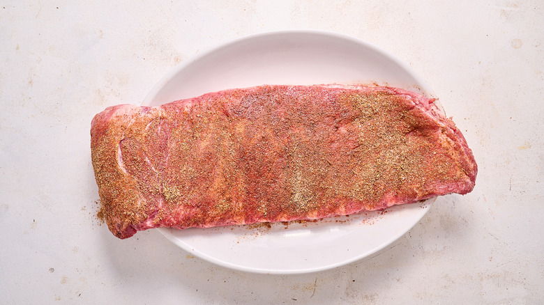 uncooked spare ribs rubbed with spices on an oval plate