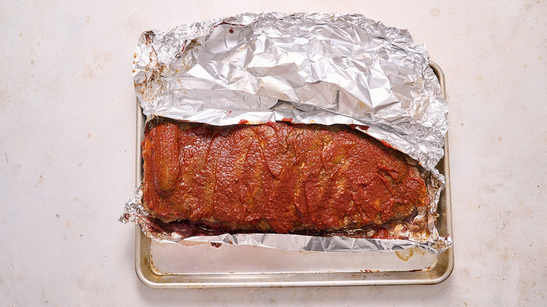 ribs brushed with barbecue sauce on foil over a baking sheet