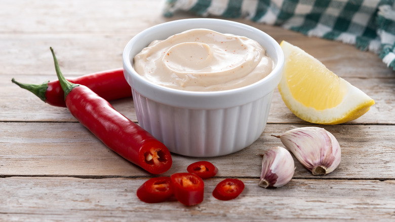 chipotle crema in a ramekin surrounded by a red pepper, garlic, and citrus wedge