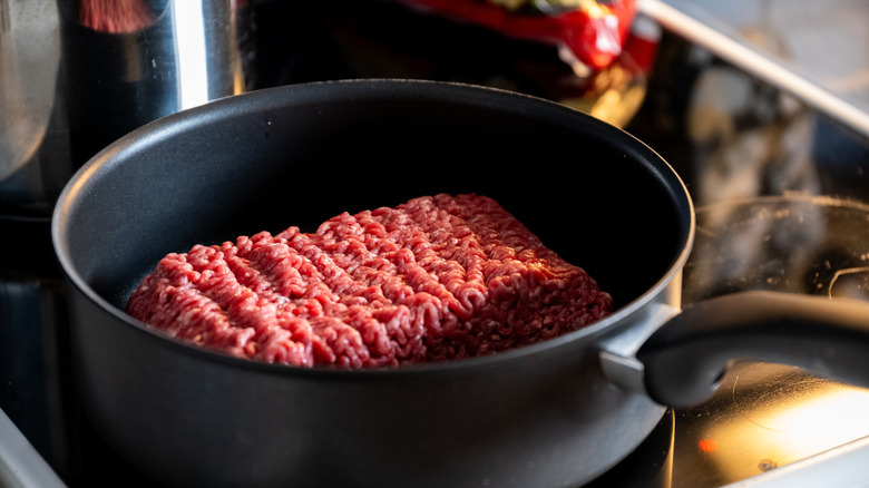 cooking a block of ground beef in pan