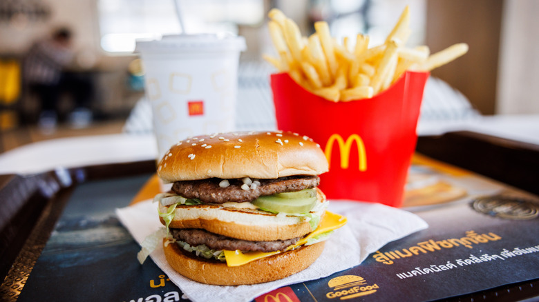 McDonald's Big Mac sitting on a tray with fries and a drink in the background