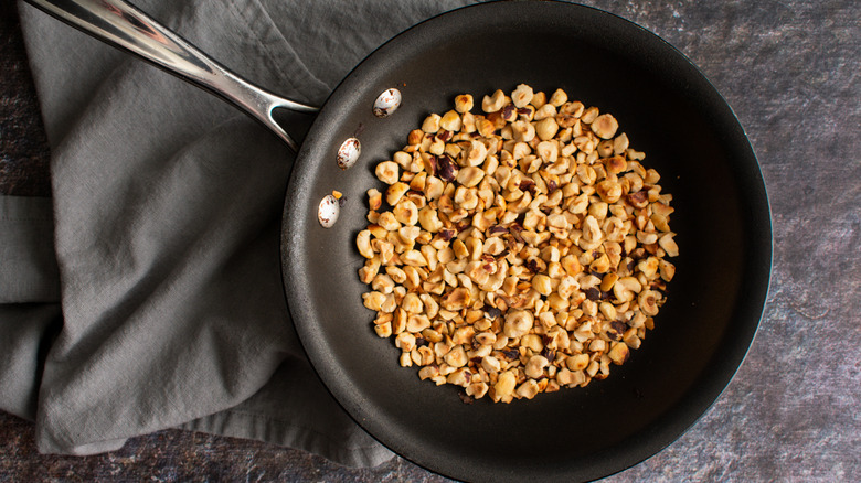 Chopped nuts in skillet on a slate background with a charcoal linen