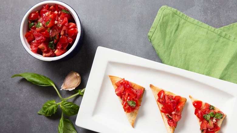 Bruschetta in bowl and bruschetta toasts on plate