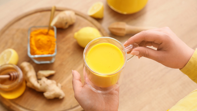 hands holding cup of tumeric tea with mik