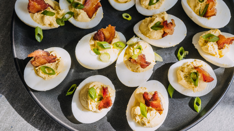 tray of deviled eggs with bacon and green onion