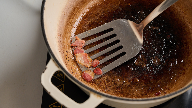 removing bacon from a pot with a spatula