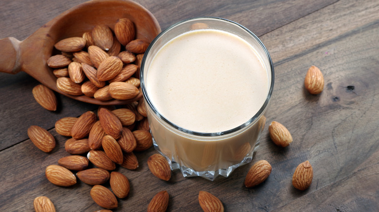 Almond milk with nuts on wood surface