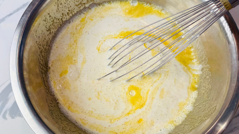 Milky egg mixture with whisk in bowl