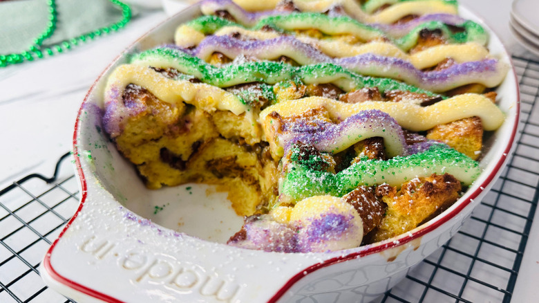 Mardi Gras king cake bread pudding in baking dish with portion removed