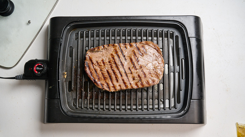 cooking the opposite side of the steak on a grill