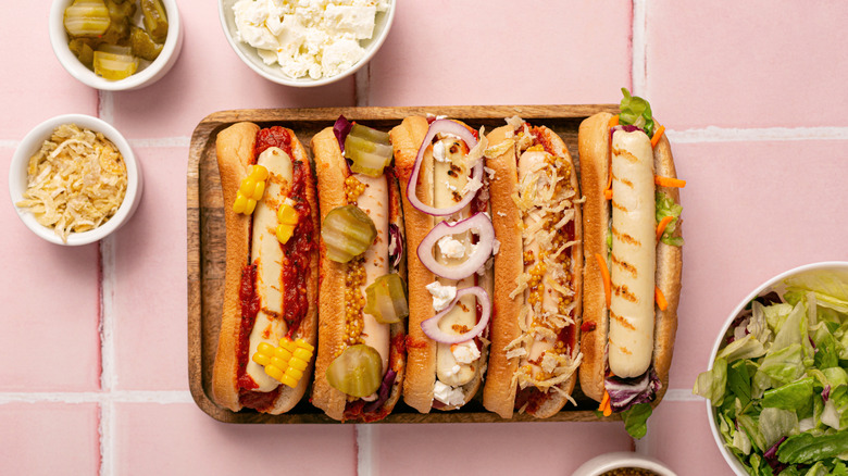 different styles of hot dogs on wooden tray