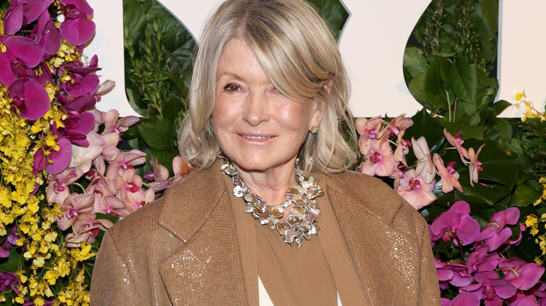 Martha Stewart stands in front of a floral display at a public function