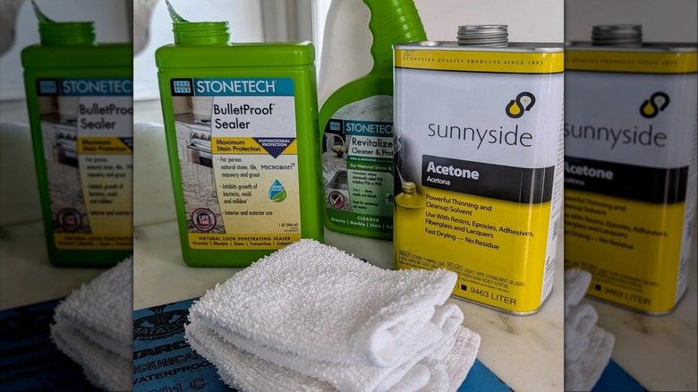 Marble cleaning and sealing products lined up on a counter next to a white cloth