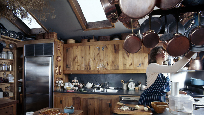 Martha Stewart haning pots and pans in her home kitchen, 70s