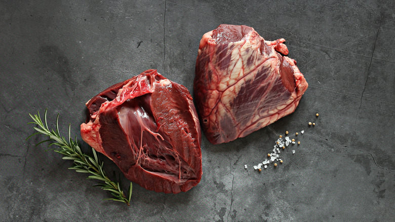 Raw beef hearts on a dark surface